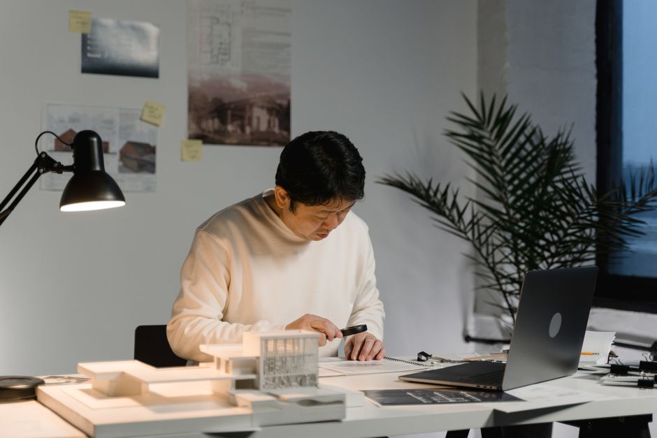 An architect's desk with modern building blueprints and a digital tablet, representing the strategic planning and auditing of digital assets.